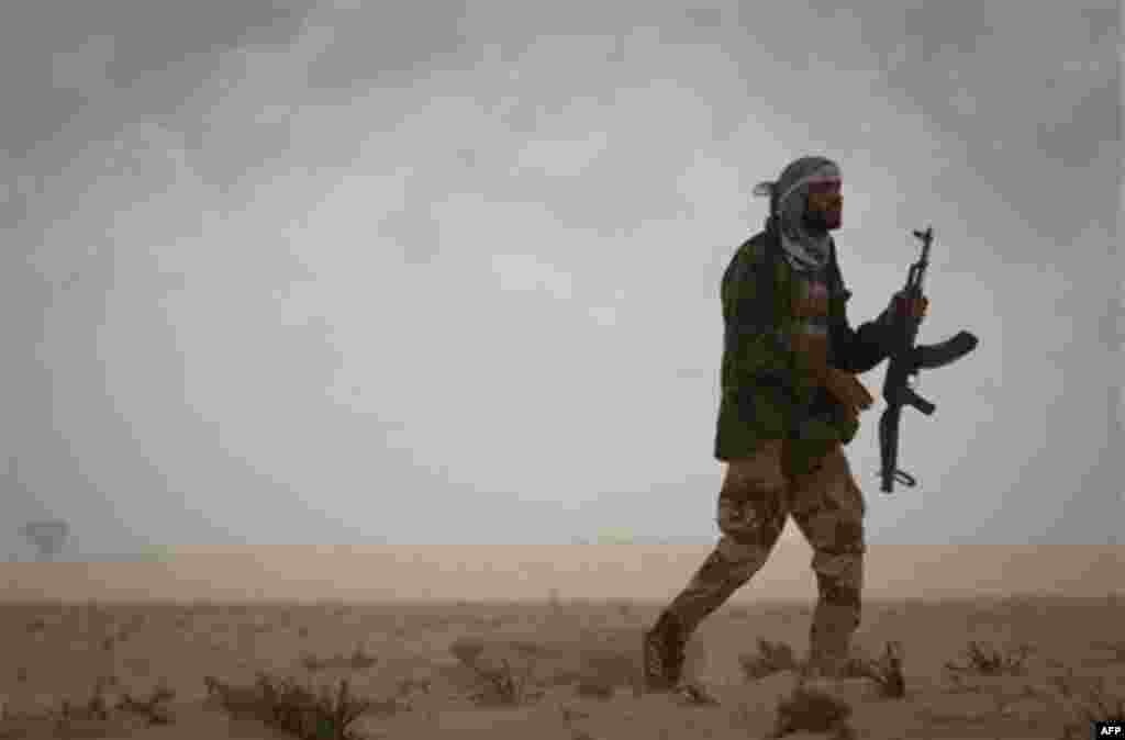 A Libyan rebel patrols the frontline of the outskirts of the city of Ajdabiya, south of Benghazi, eastern Libya, Monday, March 21, 2011. The international military intervention in Libya is likely to last "a while," a top French official said Monday, echoi