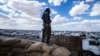 (FILE) A member of Kurdish internal security forces watches as another group of Syrian families is released from the Kurdish-run al-Hol camp in Hasakeh governorate of northeastern Syria, on March 18, 2021.