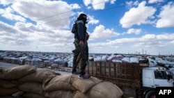 (FILE) A member of Kurdish internal security forces watches as another group of Syrian families is released from the Kurdish-run al-Hol camp in Hasakeh governorate of northeastern Syria, on March 18, 2021.