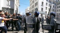 FILE - Demonstrators face police officers as they march in the streets in support of the Hirak pro-democracy movement, in Algiers, May 7, 2021.