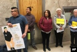 FILE - Andrew Medina, left, holds a sign during a rally backing a pardon for Borey Ai, Oct. 24, 2018, in Sacramento, Calif.