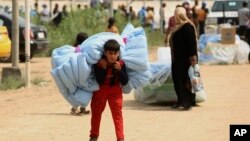 FILE - Iraqis internally displaced carry humanitarian aid being distributed at a refugee camp in Iraq.