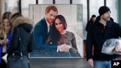 People walk past a picture of Britain's Prince Harry and Meghan Duchess of Sussex, in Windsor, Friday, Jan. 10, 2020.