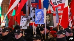 Pro-government activists hold portraits of some of the victims of the 1981 martial law crackdown and shout slogans at a passing anti-government march through downtown Warsaw on the 35th anniversary of the event, Dec. 13, 2016. 