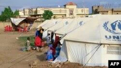 (FILE) People already displaced by conflict, rest by tents at a makeshift campsite they were evacuated to following deadly floods in the eastern city of Kassala on August 11, 2024.