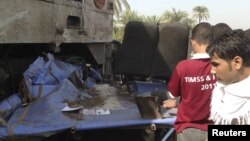 Relatives of victims look at the wreckage of a bus after a train (L), with bloodstains, crashed into it at Manflot in the southern city of Assuit, 500 km (310 miles) south of Cairo, November 17, 2012. Forty-nine people, mostly children, were killed when t