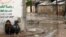 FILE - Palestinian boys sit on a sidewalk on a rainy day in Beit Hanoun in the northern Gaza Strip, Jan. 24, 2016. 