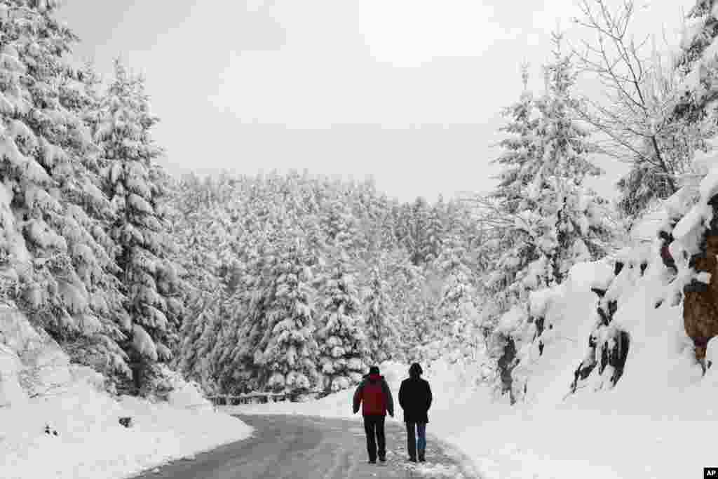 Dua pria berjalan di jalanan Sarajevo, Bosnia, di mana temperartur yang beku menyebabkan wilayah Bosnia dilanda salju saat musim semi.