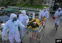 Medical personnel in protective gear transport a coronavirus patient to an ambulance boat, on Marajo island, Para state, Brazil, May 25, 2020.
