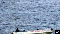 An armed suspected pirate looks over the edge of a skiff, in international waters off the coast of Somalia.