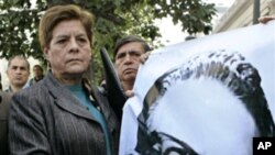 A member of Chile's Communist Party of the late President Salvador Allende holds an image of him during a gathering to commemorate the 36th anniversary of the election that led Marxist leader Salvador Allende to the presidency, in front of the La Moneda g