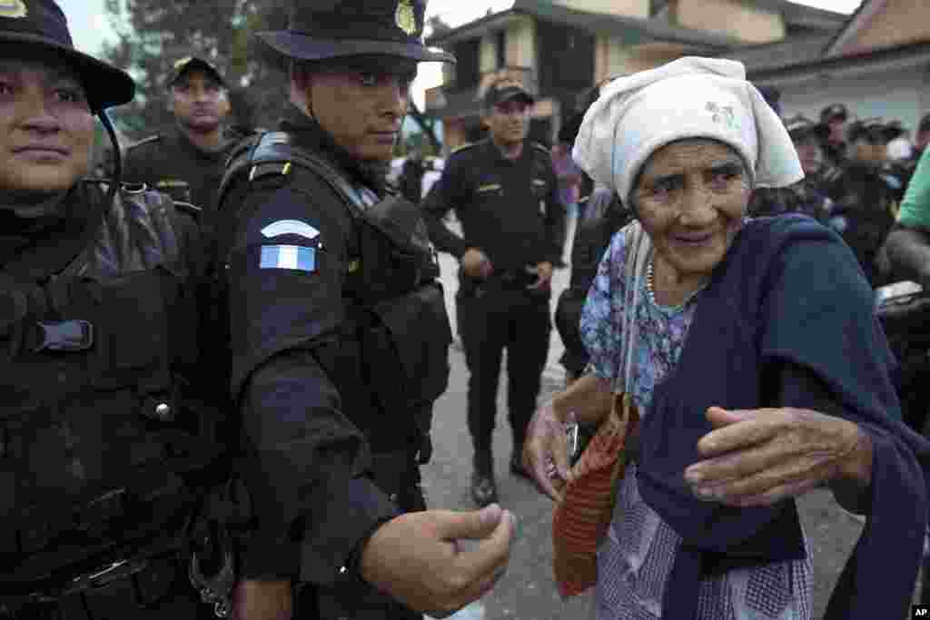 An elderly Honduran migrant woman talks with Guatemalan police who temporarily block the road to keep her and her caravan from advancing, in Esquipulas, Guatemala, Oct. 15, 2018. 