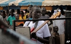 In this photo taken Saturday, Nov. 5, 2016, a guitarist at an Ana Taban, or "I am tired" artists movement roadshow, plays in front of an audience in Juba, South Sudan. For many in South Sudan, the arts have become a rare haven of peace in a young country that has known little but civil war.
