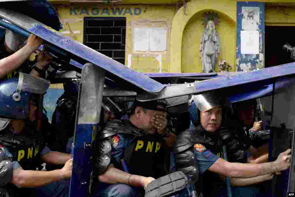 Policemen use their shields during the demolition of an informal settler community in Manila, Philippines, to redevelop the area into a business district in a joint venture with a private firm. Some 500 families were affected by the demolition.