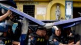 Policemen use their shields during the demolition of an informal settler community in Manila, Philippines, to redevelop the area into a business district in a joint venture with a private firm. Some 500 families were affected by the demolition.