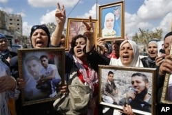 Palestinian women hold portraits of relatives held in Israeli jails during a protest calling for the release of Palestinian prisoners, in the West Bank city of Nablus, Tuesday 6 Oct. 2009