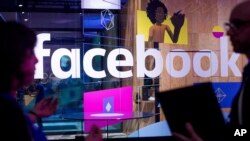 Para petugas di konferensi berbicara di depan stand demo di ajang tahunan Facebook F8 Developer Conference yang diselenggarakan hari Selasa, 18 April 2017 di San Jose, California (foto: AP Photo/Noah Berger)