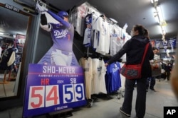 Customers shop for goods related to Shohei Ohtani of the Los Angeles Dodgers at a sporting goods store, "SELECTION," in Shinjuku district Wednesday, Oct. 23, 2024 in Tokyo. (AP Photo/Eugene Hoshiko)