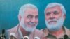 Sebuah mural yang menunjukkan wajah Jenderal Qassem Soleimani dan pemimpin komando milisi Irak Abu Mahdi al-Muhandis, terpampang di salah satu area di Baghdad dalam foto yang diambil pada 3 Januari 2021. (Foto: Reuters/Thaier Al-Sudani)