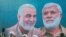 Sebuah mural yang menunjukkan wajah Jenderal Qassem Soleimani dan pemimpin komando milisi Irak Abu Mahdi al-Muhandis, terpampang di salah satu area di Baghdad dalam foto yang diambil pada 3 Januari 2021. (Foto: Reuters/Thaier Al-Sudani)
