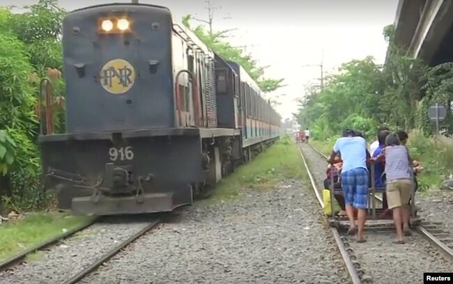 Commuters ride wooden carts pushed along the railroad tracks to avoid Manila's infamous traffic gridlock.