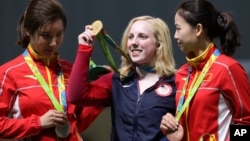 Virginia Thrasher, center, of the United States holds her gold medal for the Women's 10m Air Rifle competition during the award ceremony at the 2016 Summer Olympics in Rio de Janeiro, Brazil, Aug. 6, 2016.
