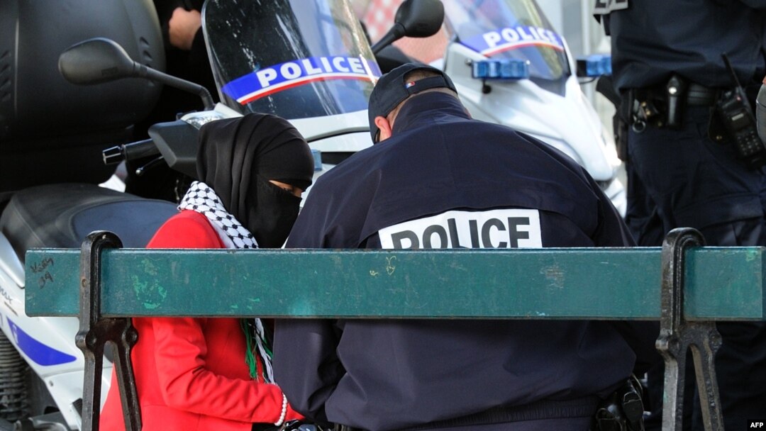 FILE - A French police officer speaks with a veiled Muslim woman during an identity check in Lille Sept. 22, 2012.