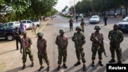 FILE - Nigerian army soldiers stand guard as they cordon off a road leading to the scene of a blast at a business district in Abuja.
