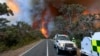 In this photo released by the State Control Centre, Country Fire Authority personnel watch as smoke billows from an out-of-control bushfire in Grampians National Park, in Victoria state, Australia, Dec. 20, 2024. 