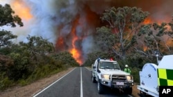 In this photo released by the State Control Centre, Country Fire Authority personnel watch as smoke billows from an out-of-control bushfire in Grampians National Park, in Victoria state, Australia, Dec. 20, 2024. 