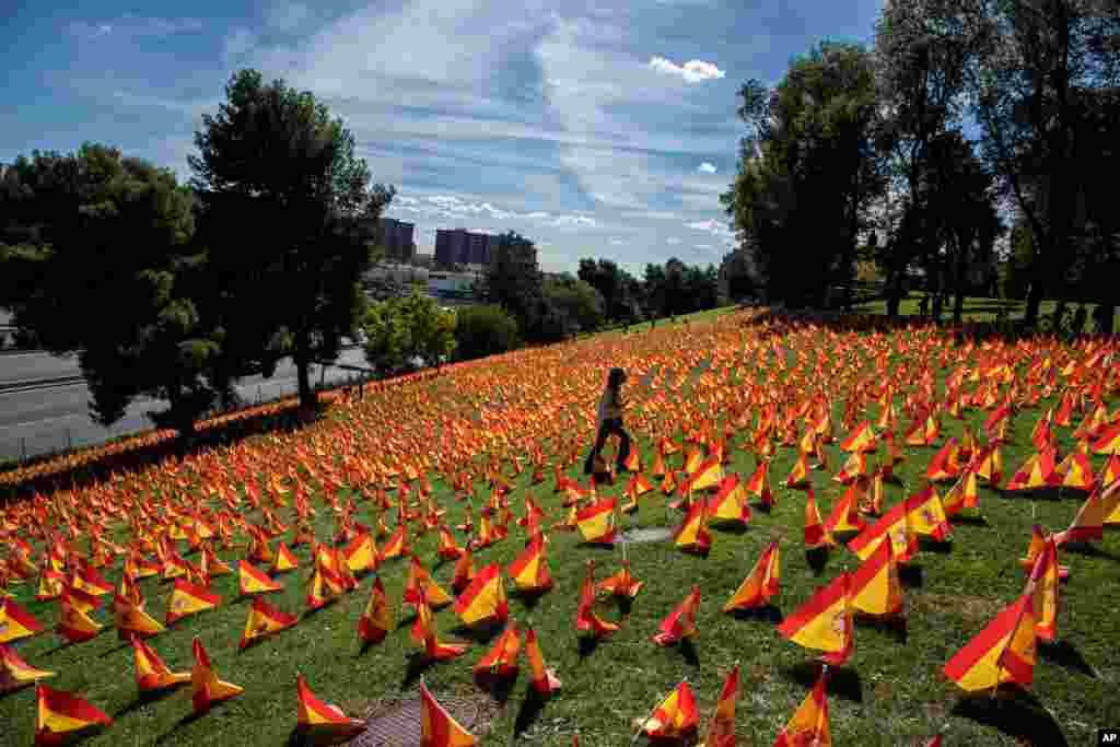 A woman walks through the flags placed in memory of coronavirus (COVID-19) victims in Madrid, Spain.