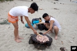 North Korean men prepare to barbecue duck meat on the seashore near Mount Chilbo, North Korea.