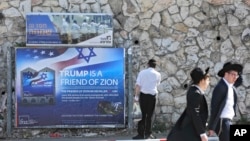 Ultra-Orthodox Jews pass by a billboard welcoming President Donald Trump ahed of his visit, in Jerusalem, May 19, 2017.