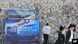 FILE - Ultra-Orthodox Jews pass by a billboard welcoming President Donald Trump ahead of his visit, in Jerusalem, May 19, 2017.