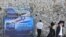 FILE - Ultra-Orthodox Jews pass by a billboard welcoming President Donald Trump ahead of his visit, in Jerusalem, May 19, 2017.