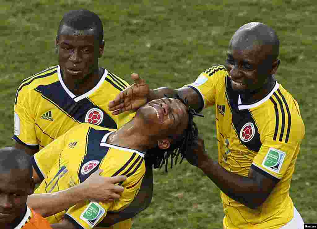 Colombia's Juan Cuadrado, center, is congratulated by his teammates Adrian Ramos, left, and Pablo Armero after he scored a goal from a penalty kick against Colombia at the Pantanal arena in Cuiaba, June 24, 2014.