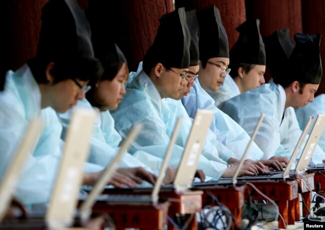 FILE - South Koreans in traditional scholar costumes use laptops at the digital version of a state examination, which were carried out during the Chosun Dynasty, at Sungkyunkwan University in Seoul May 14, 2006.