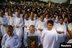 FILE - Nuns and people take part in a procession with the royal carriage containing the remains of Thailand's Supreme Patriarch, Somdet Phra Nyanasamvara Somdet Phra Sangharaja, during his cremation ceremony in Bangkok, Thailand, December 16, 2015.
