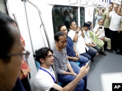 Presiden Joko Widodo (kedua dari kiri) berswafoto dengan aktor Reza Rahadian (kiri) saat menaiki Moda Raya Terpadu (MRT), Minggu, 24 Maret 2019.