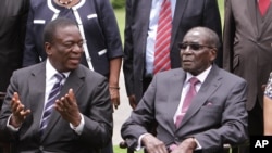 FILE PICTURE: Emmerson Mnangagwa, left, Vice President of Zimbabwe chats with Zimbabwean President Robert Mugabe after the swearing in ceremony