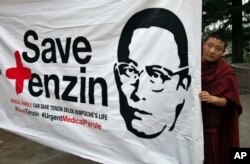 FILE - An exile Tibetan Buddhist monk holds a banner with the portrait of Buddhist leader Tenzin Delek Rinpoche who has been in a Chinese prison since 2002 on charges of “inciting separatism”, in Dharmsala, India, April 7, 2015.