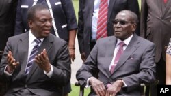 FILE: Emmerson Mnangagwa, left, then Vice President of Zimbabwe chats with Zimbabwean President Robert Mugabe after the swearing in ceremony at State House in Harare, Friday, Dec, 12, 2014.