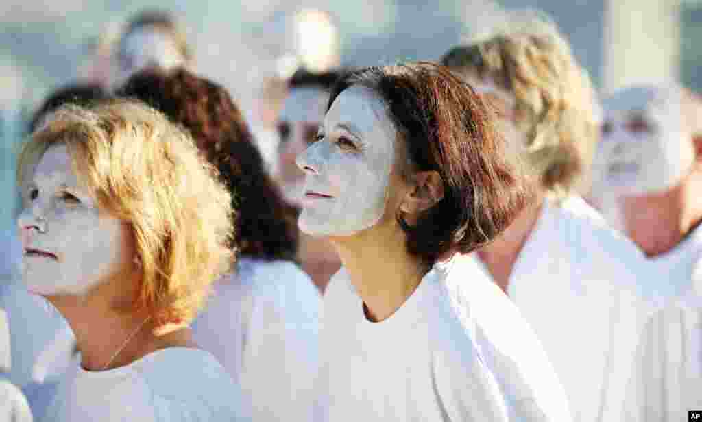 Demonstrators from the environmental group Greenpeace paint their faces white to highlight coral bleaching in Sydney, Australia, on Earth Day.