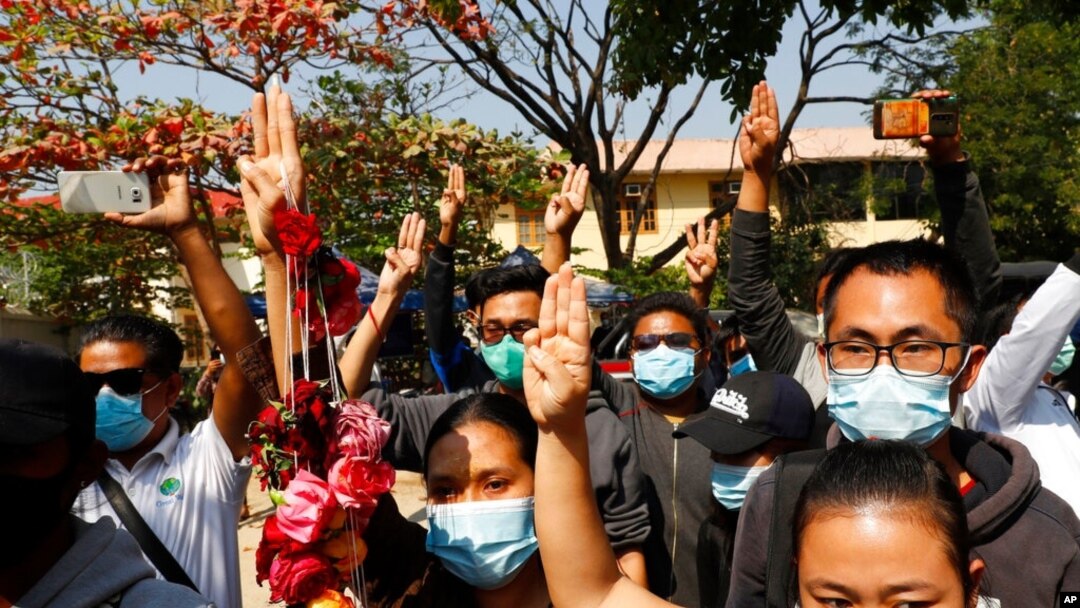 Supporters show a three-finger salute of protest while four arrested activists appear in court in Mandalay, Myanmar, Feb. 5, 2021. Hundreds of students and teachers have taken to Myanmar's streets to demand the military return power to elected officials.