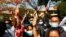 Supporters show a three-finger salute of protest while four arrested activists appear in court in Mandalay, Myanmar, Feb. 5, 2021. Hundreds of students and teachers have taken to Myanmar's streets to demand the military return power to elected officials.