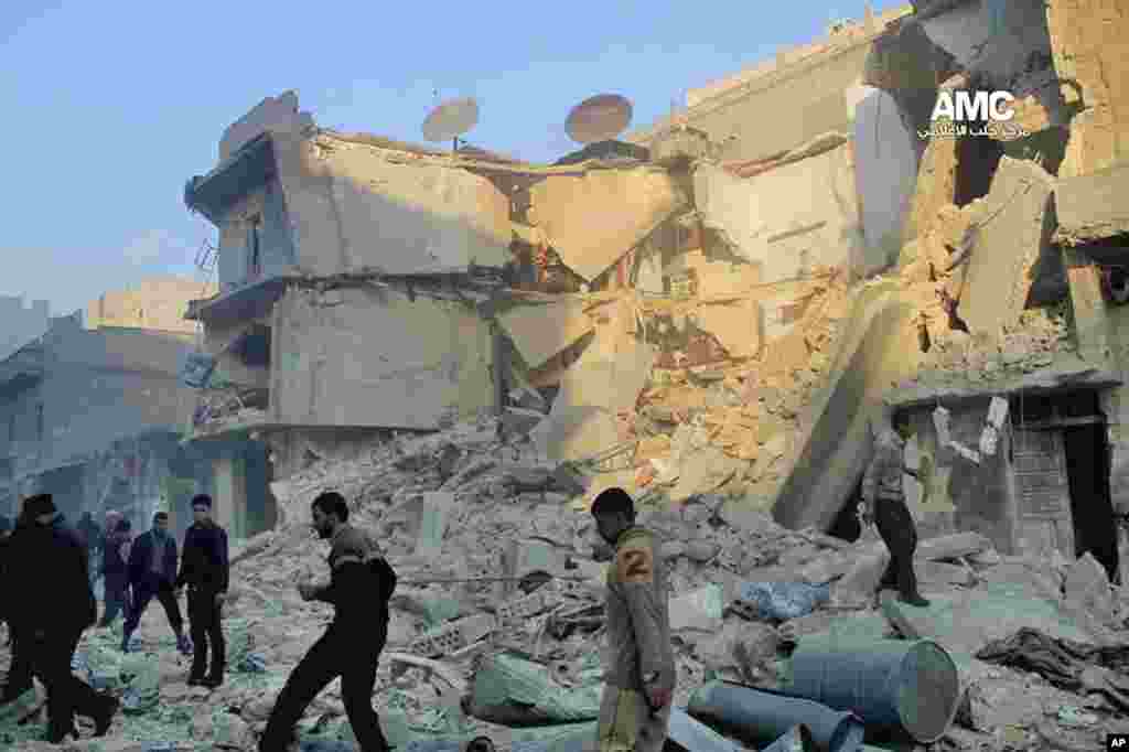 This citizen journalism image provided by Aleppo Media Center shows Syrians inspecting the rubble of damaged buildings following a government airstrike in Aleppo, Dec. 15, 2013.