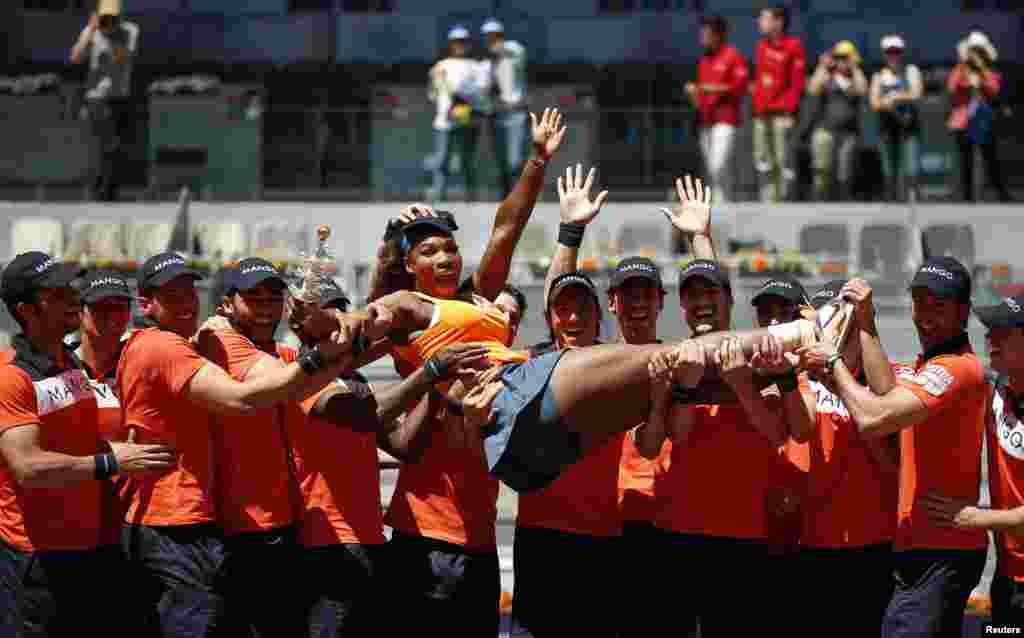 Serena Williams of the U.S. is lifted up in the air by ball boys as she poses with the Ion Tiriac&#39;s trophy after winning the Madrid Open tennis tournament in Madrid, Spain. 