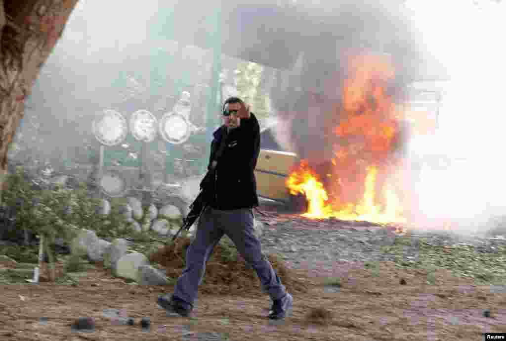 An Israeli police officer gestures in front of a burning car after a rocket fired by Palestinian militants in Gaza landed in the southern city of Ashkelon, November 18, 2012. (Reuters)