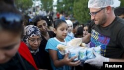 FILE - Syrian migrants queue to get food from a local NGO on the side of a highway near Edirne in Turkey, as they rest from their travel towards the Greek border, Sept. 17, 2015. 