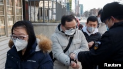 신종 코로나바이러스 확산 우려가 높은 중국에서, 3일 베이징의 한 건물 보안요원이 출근하는 직장인들의 체온을 재고 있다.